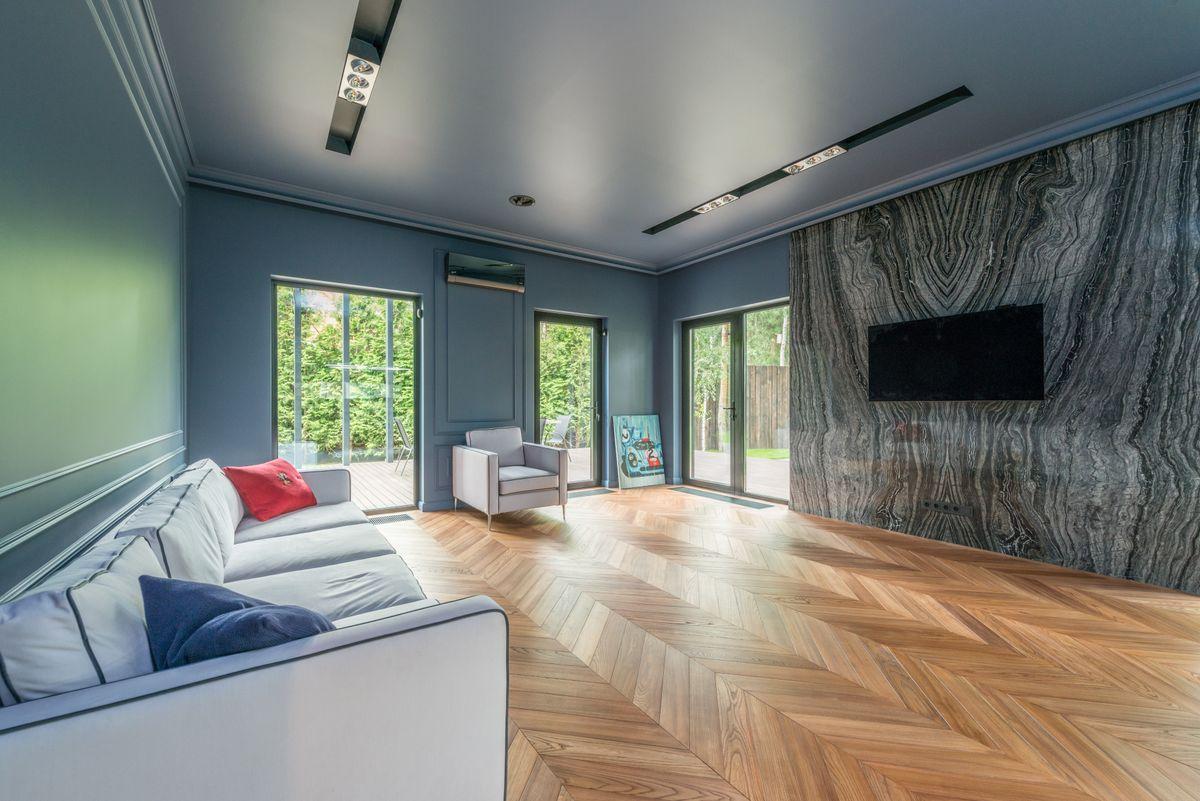 A light-filled living room with wooden floors and garden views